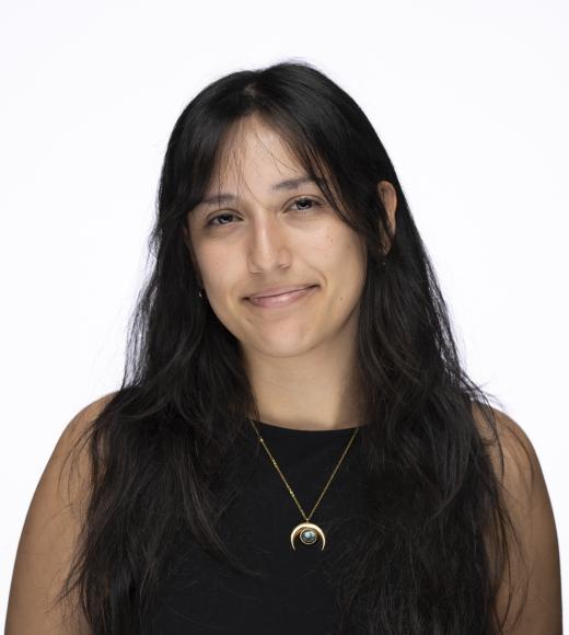 Head-and-shoulders studio portrait of smiling woman with long dark hair and crescent necklace